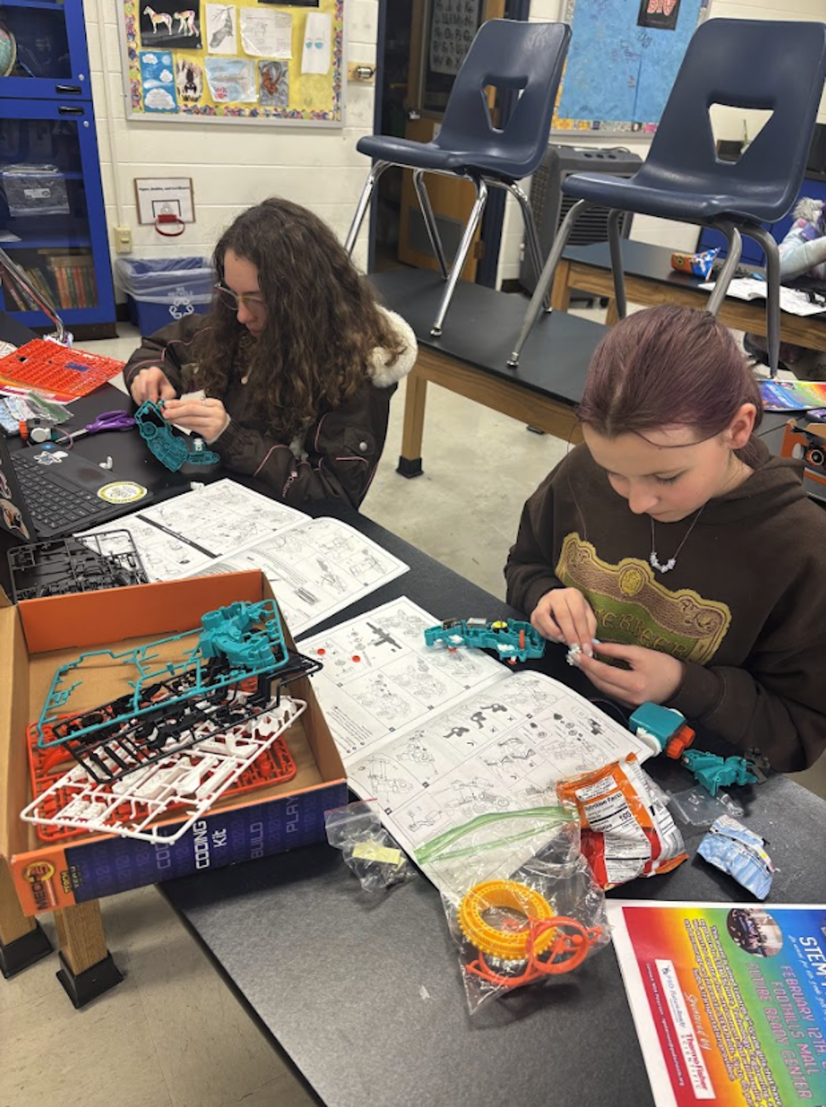 A group of four professionals, two men and two women, are gathered around a conference table reviewing printed charts and documents.