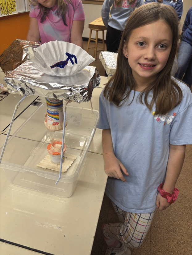 Two young professionals working together at a desk with multiple laptops and a tablet