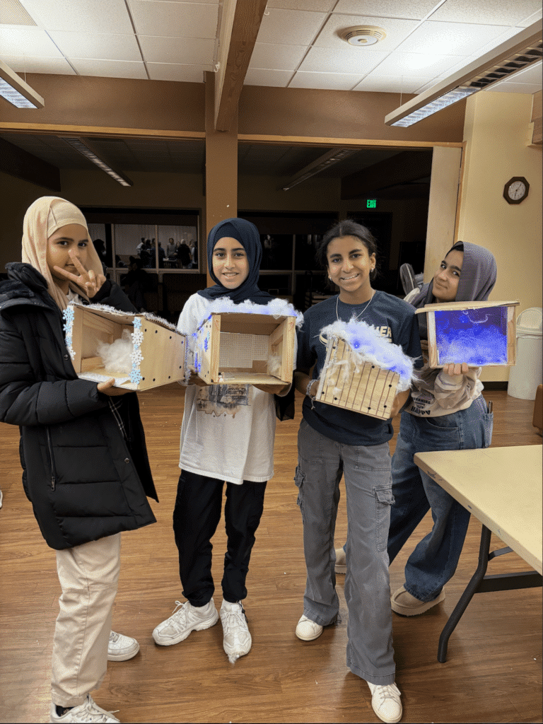 Two young professionals working together at a desk with multiple laptops and a tablet