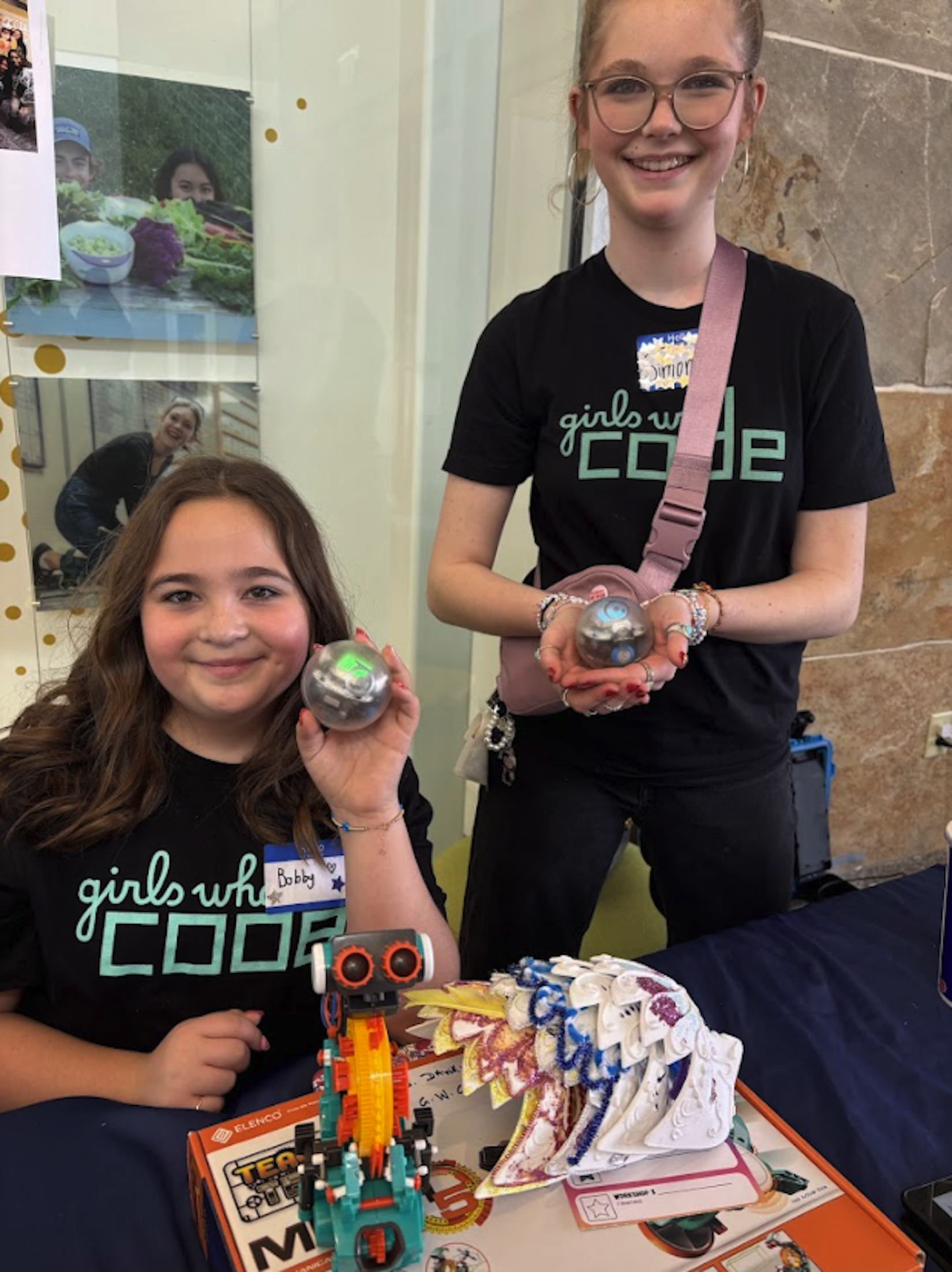 Two young professionals working together at a desk with multiple laptops and a tablet